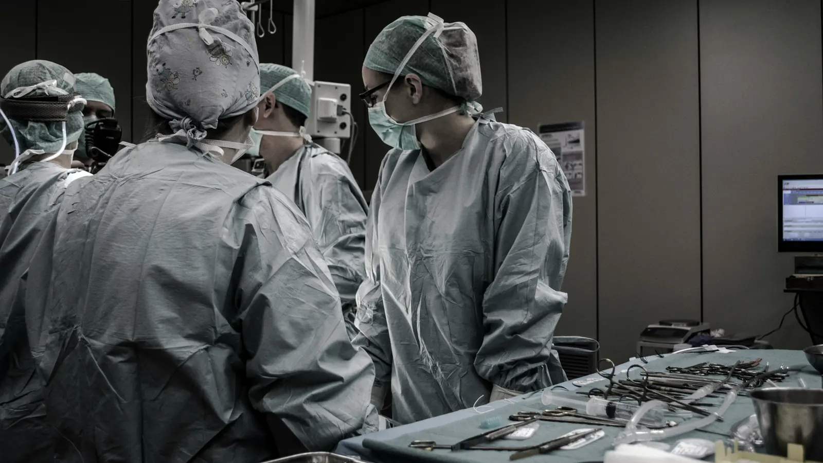 A surgical team at work around the table, instruments laid out in the foreground